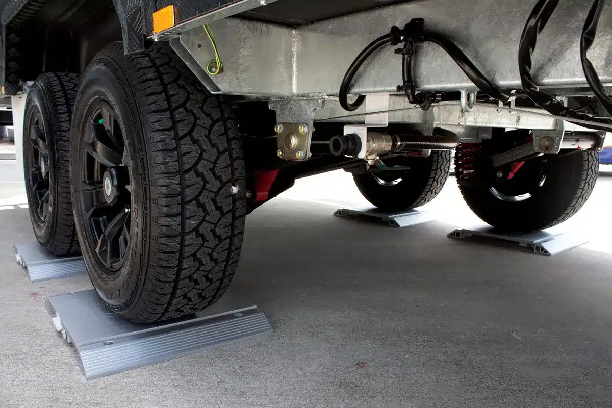 Caravan wheels and chassis positioned on portable scale pads for an accurate weight reading