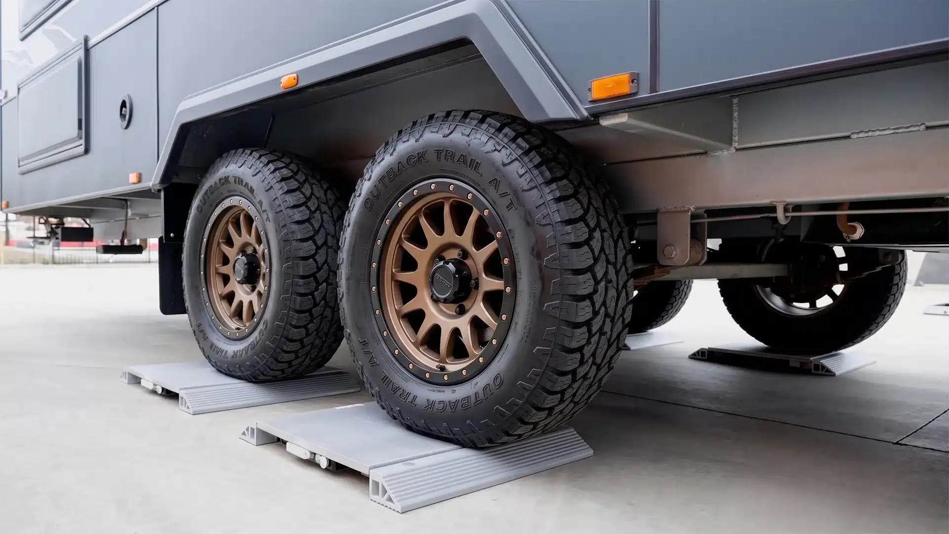 Off-road caravan's dual-axle wheels resting on portable weighbridge scales for a weight check