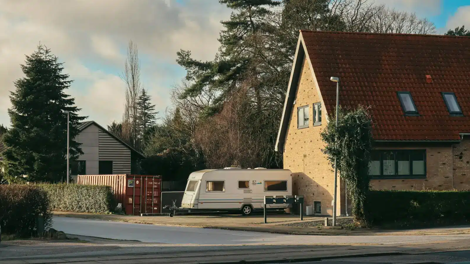 Caravan parked in a driveway beside a brick house