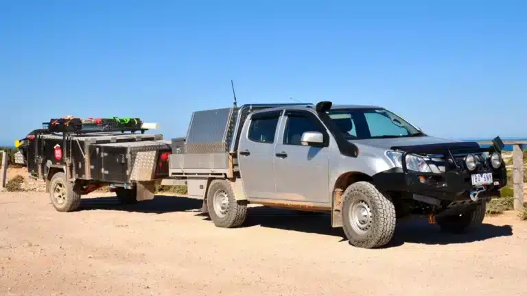 Silver Isuzu D-Max dual cab with a tray canopy hitched to a camper trailer at a clifftop lookout on the Nullarbor