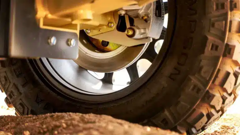 Close-up of an off-road caravan wheel showing the hub, disc brake and caliper behind a chunky all-terrain tyre