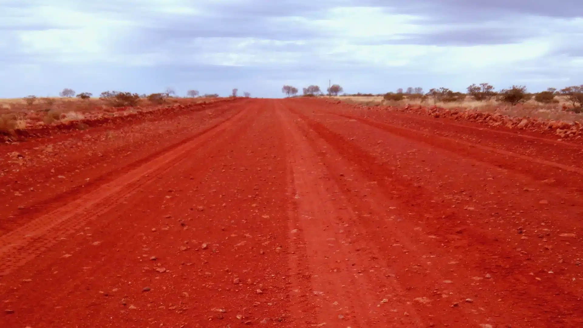 oodnadatta-track-red-gravel-road Straight red gravel road with wheel ruts running through low scrub on the Oodnadatta Track in South Australia