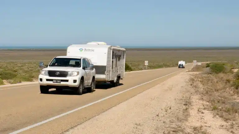 White Toyota LandCruiser towing a caravan along the Eyre Highway near Eucla, Western Australia